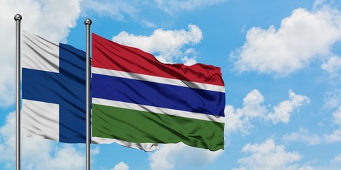 Finland and Gambia flag waving in the wind against white cloudy blue sky together. Diplomacy concept, international relations.