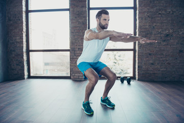 Full length photo of handsome trainer guy doing static squats concentrated sportswear tank-top...