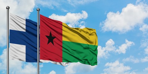 Finland and Guinea Bissau flag waving in the wind against white cloudy blue sky together. Diplomacy concept, international relations.
