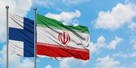 Finland and Iran flag waving in the wind against white cloudy blue sky together. Diplomacy concept, international relations.