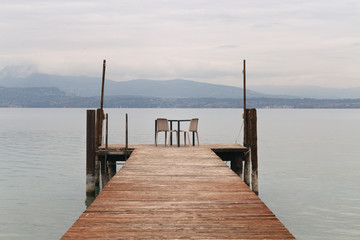 Obraz premium Garda Lake pier, view of Lake Garda and Alps