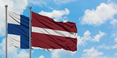 Finland and Latvia flag waving in the wind against white cloudy blue sky together. Diplomacy concept, international relations.