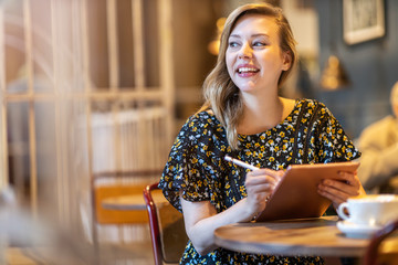 Female designer sketching with digital tablet and stylus at cafe