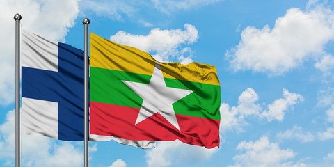 Finland and Myanmar flag waving in the wind against white cloudy blue sky together. Diplomacy...
