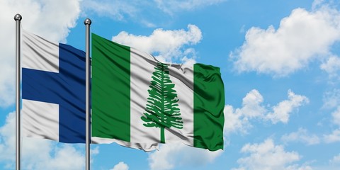 Finland and Norfolk Island flag waving in the wind against white cloudy blue sky together....