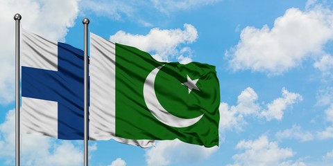 Finland and Pakistan flag waving in the wind against white cloudy blue sky together. Diplomacy...