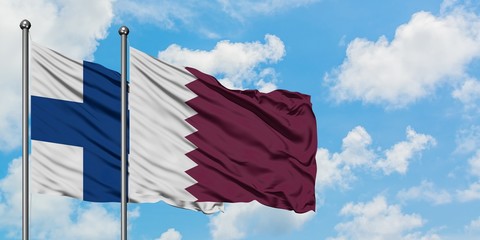 Finland and Qatar flag waving in the wind against white cloudy blue sky together. Diplomacy...