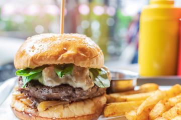 Hamburger with beef burger cutlet, blue cheese, spinach, french fries and ketchup served on tray.