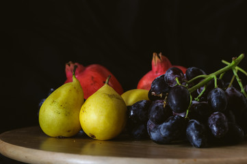 still life pears and black grapes on a black background