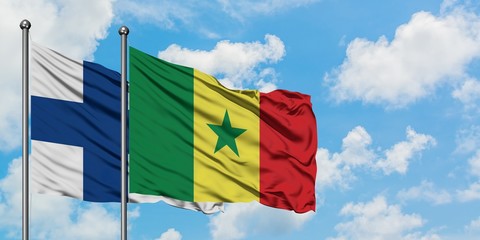 Finland and Senegal flag waving in the wind against white cloudy blue sky together. Diplomacy...