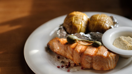 grilled salmon steak and baked potatoes with sauce