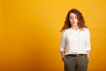 sad beautiful young girl standing isolated on yellow background.