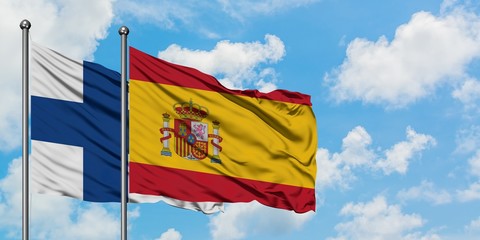 Finland and Spain flag waving in the wind against white cloudy blue sky together. Diplomacy...