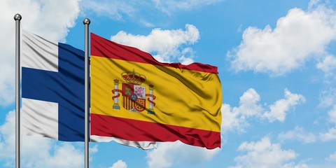 Finland and Spain flag waving in the wind against white cloudy blue sky together. Diplomacy concept, international relations.