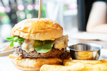 Hamburger with beef burger cutlet, blue cheese, spinach, french fries and ketchup served on tray.