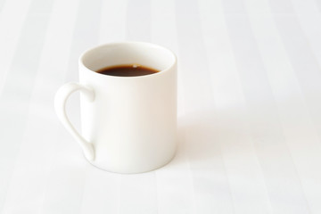 Obraz premium Black coffee cup on the bed in cozy morning with sunshine into window.