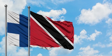 Finland and Trinidad And Tobago flag waving in the wind against white cloudy blue sky together. Diplomacy concept, international relations.
