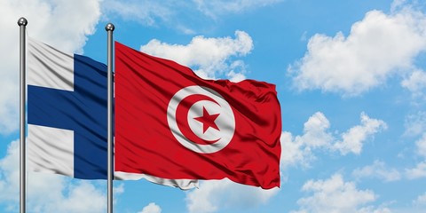 Finland and Tunisia flag waving in the wind against white cloudy blue sky together. Diplomacy concept, international relations.