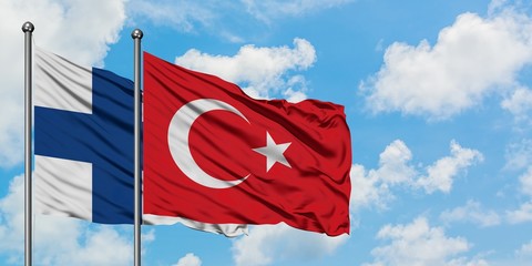 Finland and Turkey flag waving in the wind against white cloudy blue sky together. Diplomacy concept, international relations.