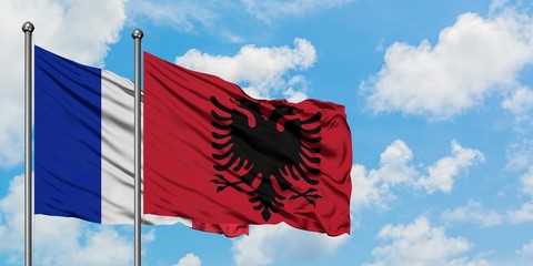 France and Albania flag waving in the wind against white cloudy blue sky together. Diplomacy concept, international relations.