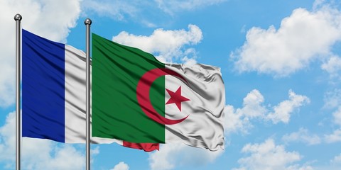 France and Algeria flag waving in the wind against white cloudy blue sky together. Diplomacy...