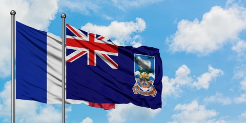 France and Falkland Islands flag waving in the wind against white cloudy blue sky together. Diplomacy concept, international relations.