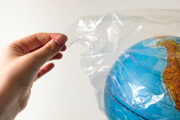 World Environment Day concept. A human hand takes off a plastic bag from the earth. There is room for text in the form for social advertising. No to plastic! Save the Earth from pollution