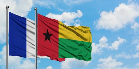 France and Guinea Bissau flag waving in the wind against white cloudy blue sky together. Diplomacy concept, international relations.