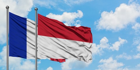 France and Indonesia flag waving in the wind against white cloudy blue sky together. Diplomacy concept, international relations.
