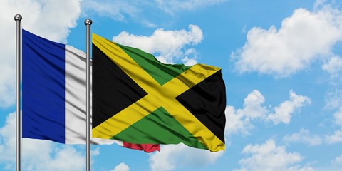 France and Jamaica flag waving in the wind against white cloudy blue sky together. Diplomacy concept, international relations.