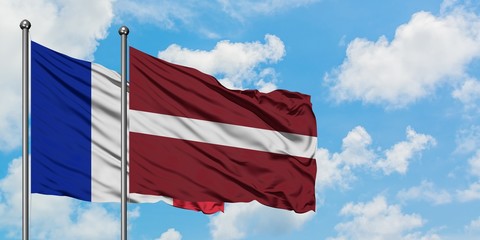 France and Latvia flag waving in the wind against white cloudy blue sky together. Diplomacy...
