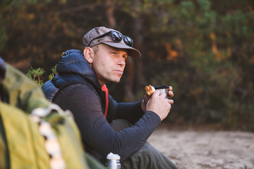 Male hiker pausing to eat and drink outdoors