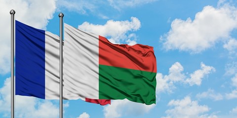 France and Madagascar flag waving in the wind against white cloudy blue sky together. Diplomacy...
