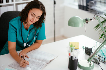Obraz premium Young female doctor in medical office. Beautiful female doctor taking notes.. 