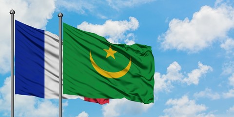 France and Mauritania flag waving in the wind against white cloudy blue sky together. Diplomacy concept, international relations.