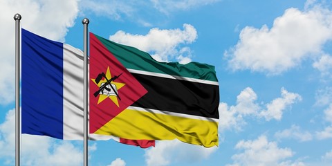 France and Mozambique flag waving in the wind against white cloudy blue sky together. Diplomacy concept, international relations.