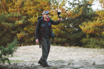 Male hiker holds stabilizer with smartphone