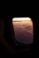 Beautiful scenic view through the aircraft window at sunset or sunrise time. Window view from passenger seat  airplane. Flying above the clouds. Panorama high above city. Vacation and travel concept.