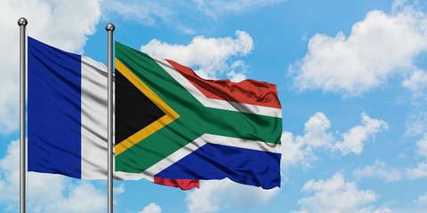 France and South Africa flag waving in the wind against white cloudy blue sky together. Diplomacy concept, international relations.