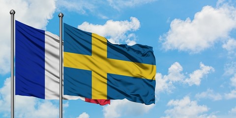 France and Sweden flag waving in the wind against white cloudy blue sky together. Diplomacy...