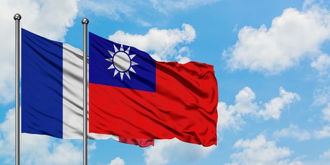 France and Taiwan flag waving in the wind against white cloudy blue sky together. Diplomacy...