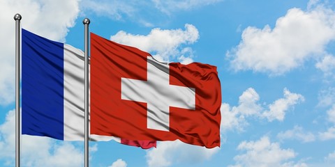 France and Switzerland flag waving in the wind against white cloudy blue sky together. Diplomacy...