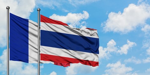 France and Thailand flag waving in the wind against white cloudy blue sky together. Diplomacy concept, international relations.