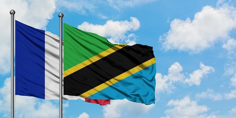 France and Tanzania flag waving in the wind against white cloudy blue sky together. Diplomacy...