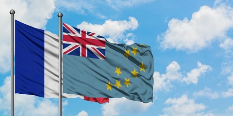 France and Tuvalu flag waving in the wind against white cloudy blue sky together. Diplomacy...