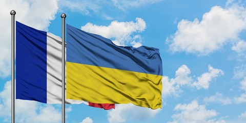 France and Ukraine flag waving in the wind against white cloudy blue sky together. Diplomacy concept, international relations.