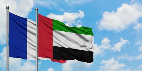 France and United Arab Emirates flag waving in the wind against white cloudy blue sky together. Diplomacy concept, international relations.