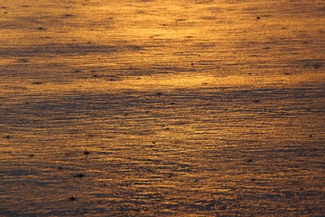 Reflection of a beautiful sunset in the waters of Lake Baikal with ripples and raindrops.