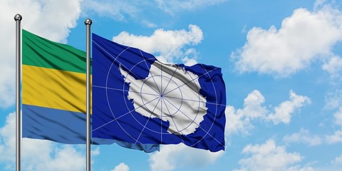 Gabon and Antarctica flag waving in the wind against white cloudy blue sky together. Diplomacy...