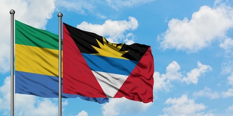 Gabon and Antigua and Barbuda flag waving in the wind against white cloudy blue sky together. Diplomacy concept, international relations.